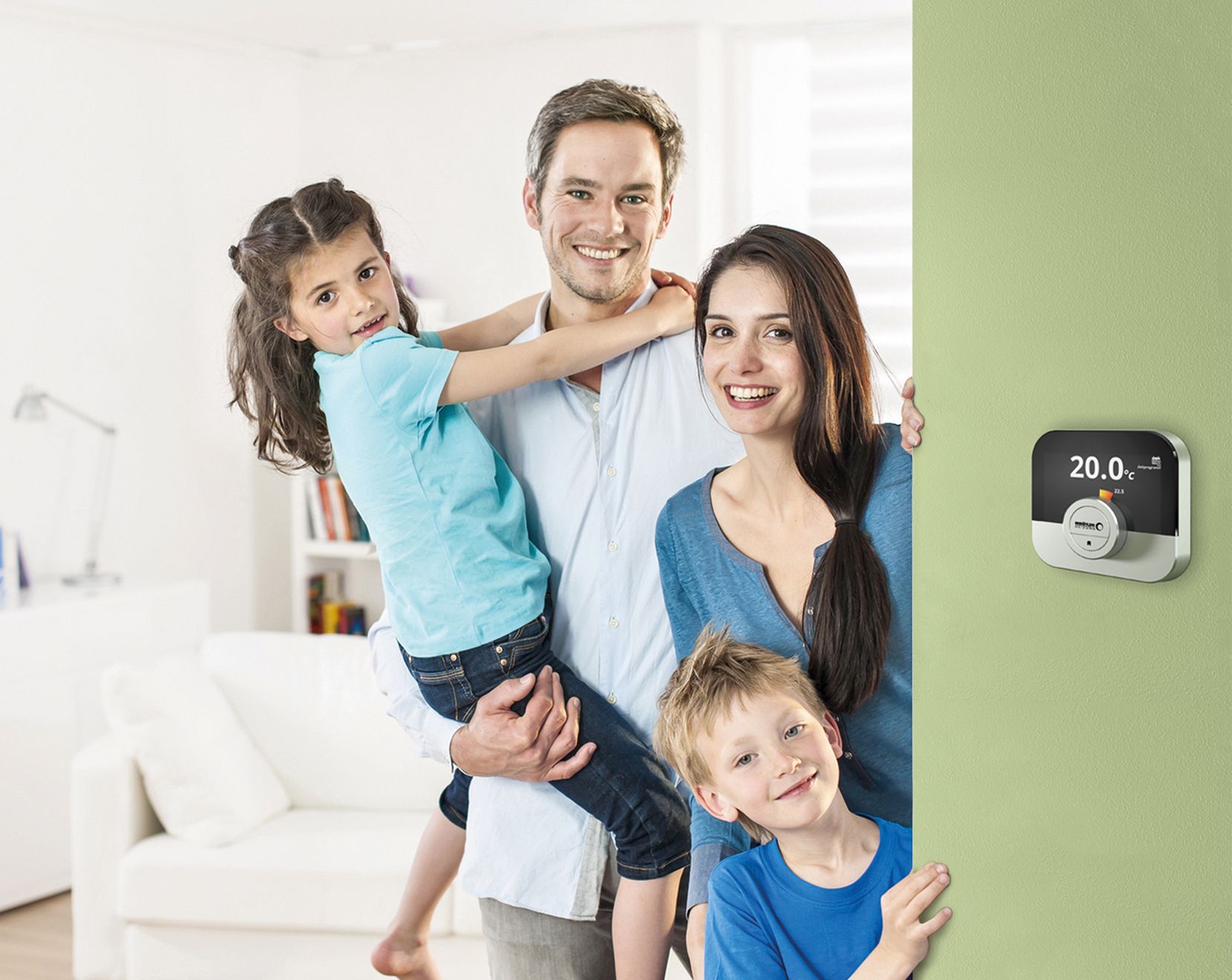 Rodzina w ciepłym domu , na ścianie regulator pogodowy Broetej IDA
